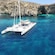 Side view of a catamaran in the water surrounded by cliffs